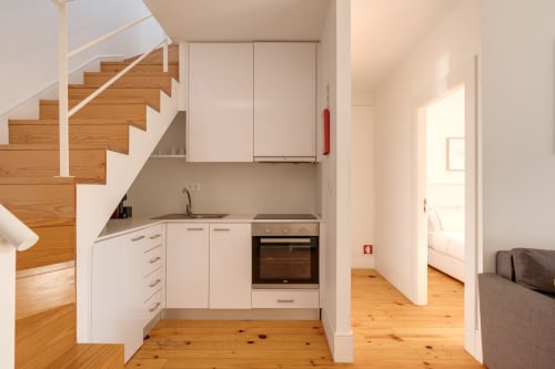 Cozinha moderna e sala de estar no duplex Bom Porto Apartments, Porto, com escadas de madeira, armários brancos e aço inoxidável