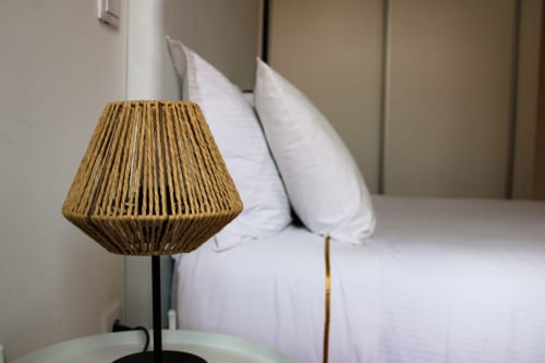 Luminária de vime tecido no quarto de hóspedes do Bom Porto Apartments com almofadas brancas e vista da cidade