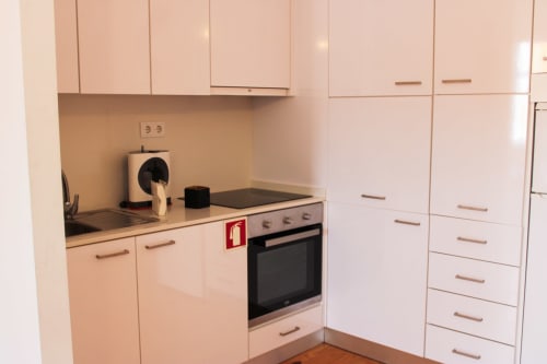 Cozinha moderna e compacta no Bom Porto Apartments no Porto com armários brancos, fogão preto e cafeteira