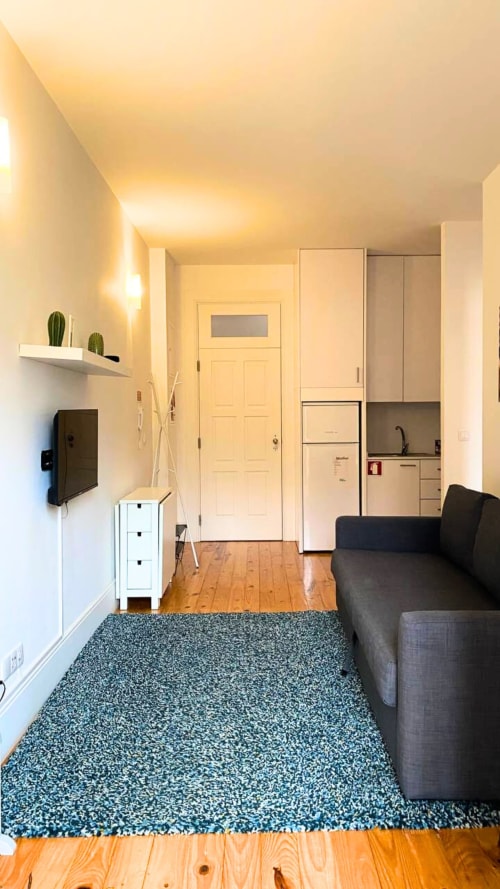 Interior moderno do apartamento estúdio em Bom Porto Apartments no Porto com cozinha, sofá preto, piso de madeira e