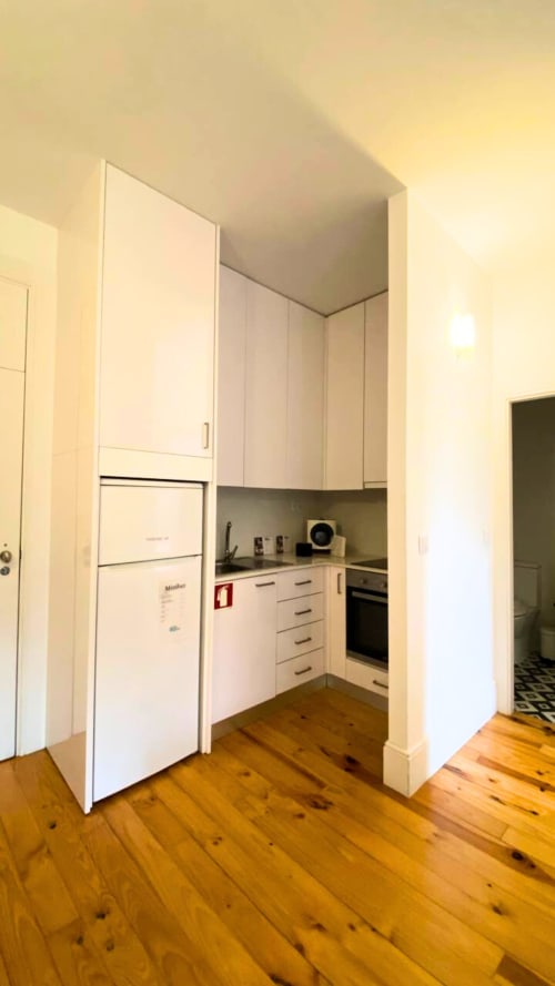 Kitchenette compacta com armários brancos, frigorífico e forno embutido no Bom Porto Apartments, Porto