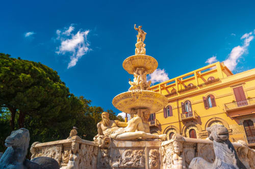 Fontana storica con sculture dorate nella piazza di Messina vicino all'hotel BellDuomo Suite, cielo azzurro limpido