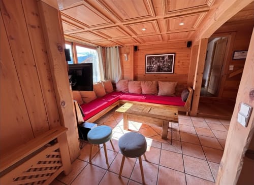 Cozy wood-paneled living room at Chez Francine with red seating, fireplace, and mountain views in Notre Dame de Bellecombe
