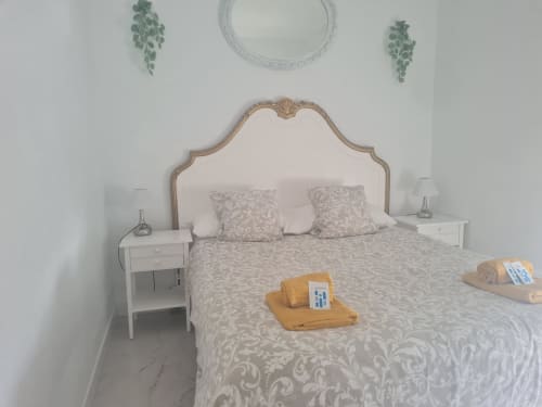 Dormitorio frente al mar en VIVE Benalmádena con cabecero ornamental, mesitas blancas y vistas al mar en Benalmádena, España