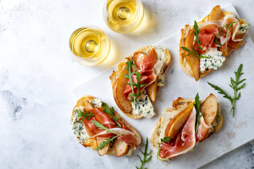 Crostini gourmet con jamón ibérico y queso del Hotel Boutique Zahara en Cádiz, acompañados de vino blanco