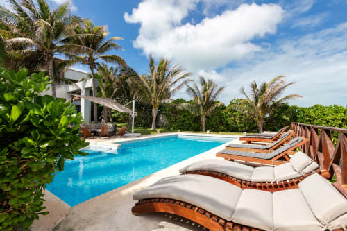 Isla Mujeres villa with turquoise pool, lounge chairs, palm trees, and sea view in Mexico