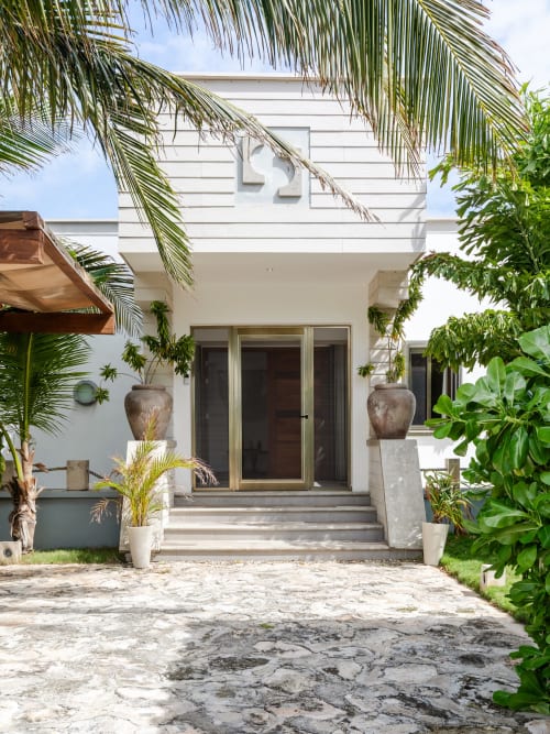 Modern beachfront villa in Isla Mujeres with white architecture, tropical palms, and sea view entrance
