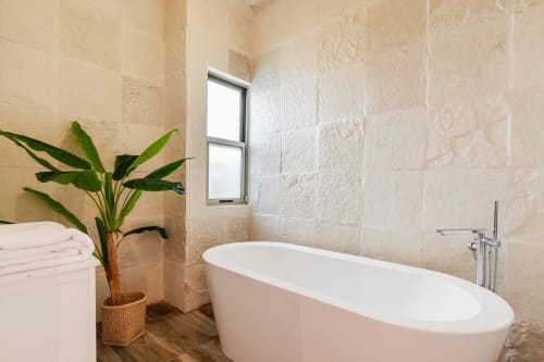Luxurious bathroom at Villa Seven, Isla Mujeres with freestanding tub, tile walls, and tropical plant decor