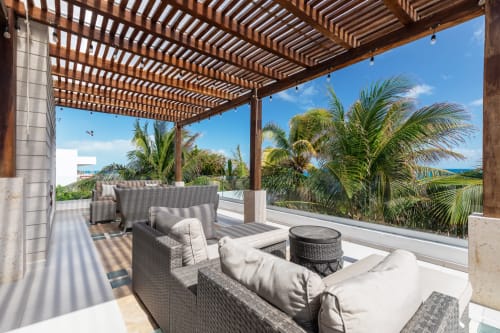 Covered patio with lounge chairs overlooking palm trees and sea view at Villa Seven, Isla Mujeres