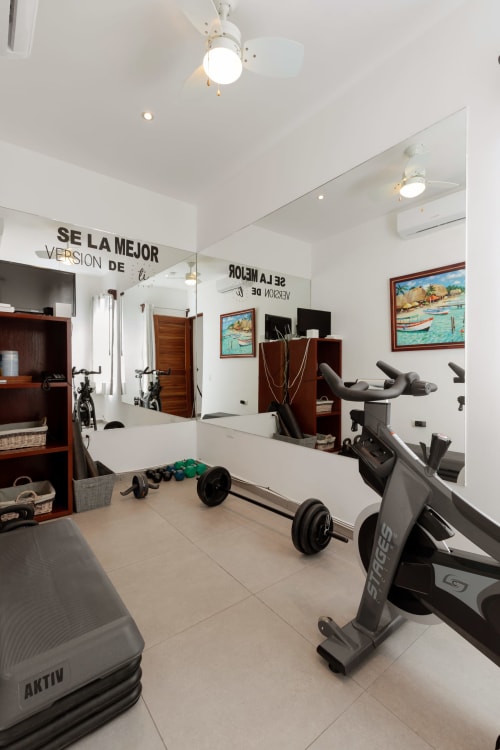 Modern home gym in Villa Seven, Isla Mujeres with stationary bikes, dumbbells, and mirrored walls