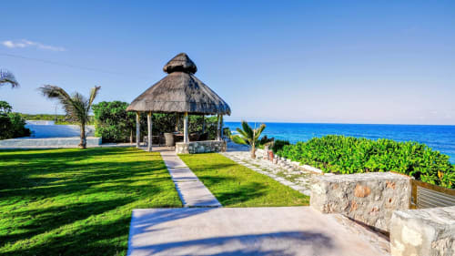 Beachfront Villa Seven in Isla Mujeres with thatched gazebo, manicured lawn, and turquoise Caribbean Sea view