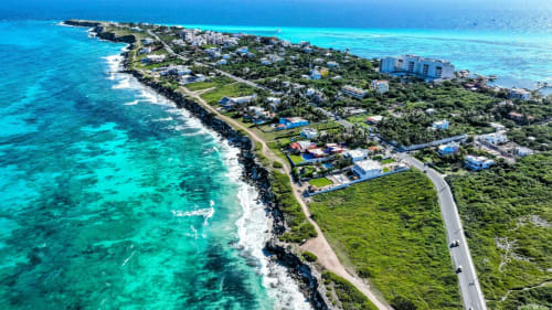Aerial view of Isla Mujeres beachfront villa with turquoise Caribbean waters, white sand beach, and lush tropical vegetation