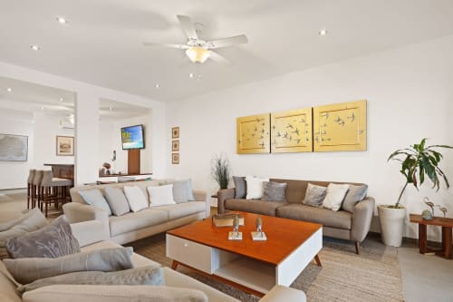 Elegant living room in Villa Seven, Isla Mujeres with beige sofas, orange coffee table, and sea view artwork