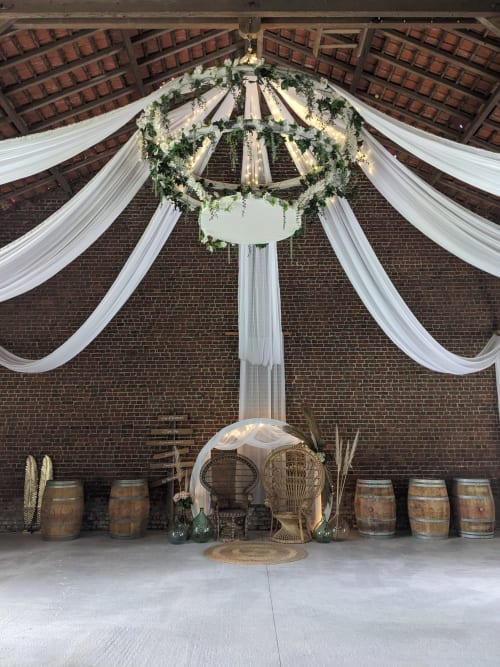 Réception de mariage élégante au Domaine De La Souche avec lustre floral, drapés blancs et tonneaux en bois