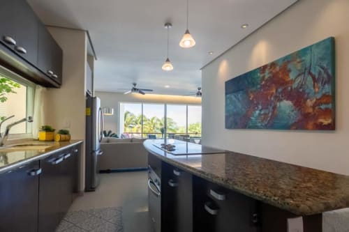 Modern kitchen with sea view at Sunset Condo Puerta al Mar, Isla Mujeres, featuring granite counters and balcony access