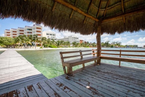 Wooden dock with bench overlooking turquoise Caribbean waters and beachfront condos in Isla Mujeres, Mexico