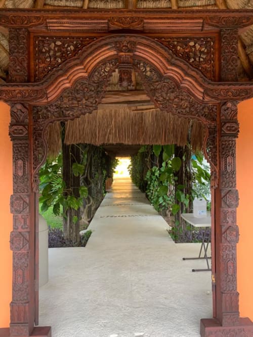 Ornate wooden archway with carved details leading to tropical garden passage at Isla Mujeres beachfront property