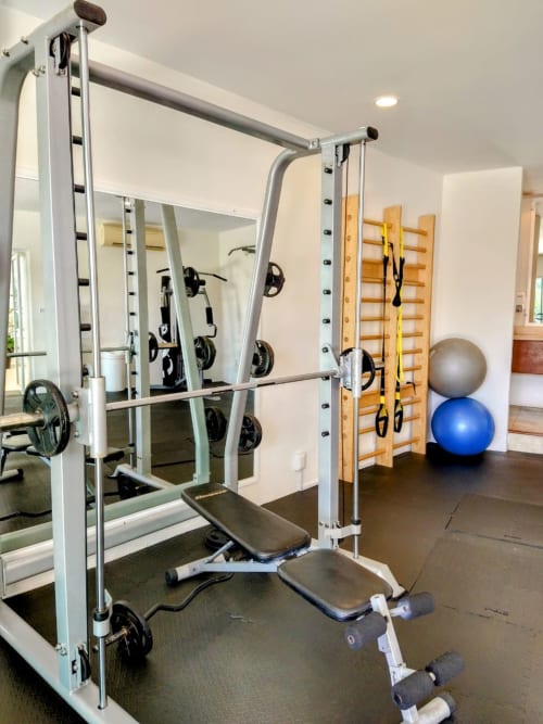 Modern home gym at Isla Mujeres Realty condo with cable machine, dumbbells, exercise balls, and wooden wall ladder