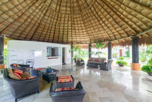 Modern beachfront condo lobby at Isla Mujeres with thatched ceiling, contemporary seating, and tropical garden views