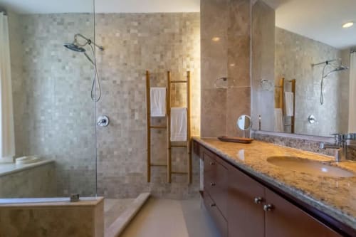 Luxe bathroom in Isla Mujeres condo with double vanity, granite counters, rainfall shower, and wooden towel ladder.