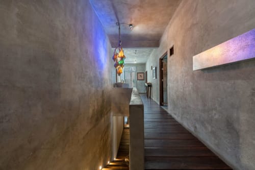 Modern hallway with concrete walls, ambient blue lighting, and a colorful hanging light fixture at Aruma Boutique Isla