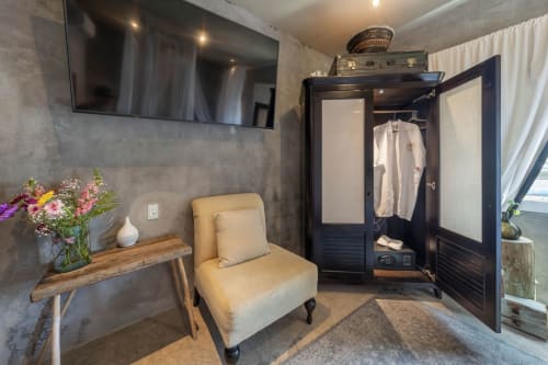 Modern villa dressing room at Aruma Boutique Isla Mujeres with cream chair, black wardrobe, and fresh flowers