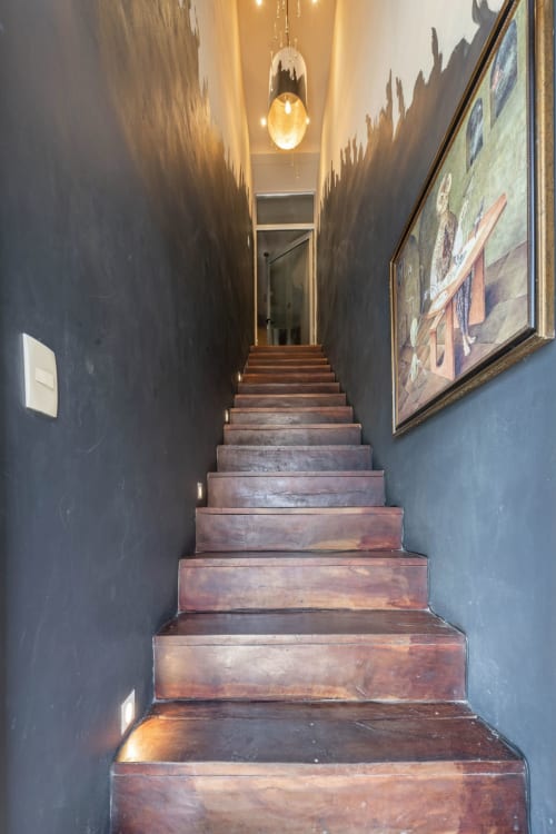 Narrow wooden staircase with dark walls and pendant lighting leading upward in Aruma Boutique villa, Isla Mujeres