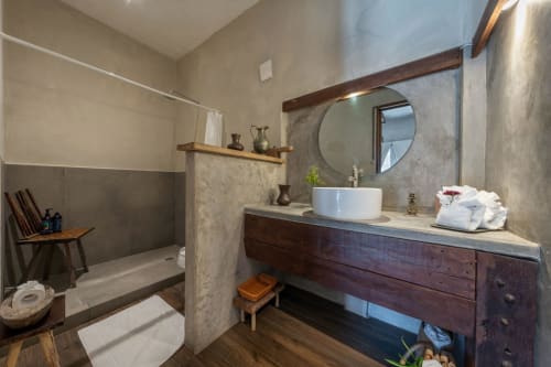 Modern bathroom in Aruma Boutique villa on Isla Mujeres with vessel sink, round mirror, wooden vanity, and walk-in shower