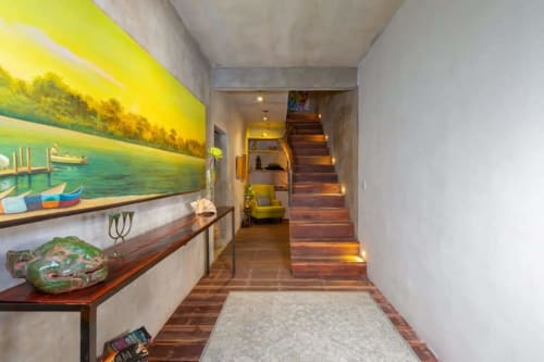 Modern hallway in Isla Mujeres villa with artwork, wooden staircase, and ambient lighting leading to bright living area