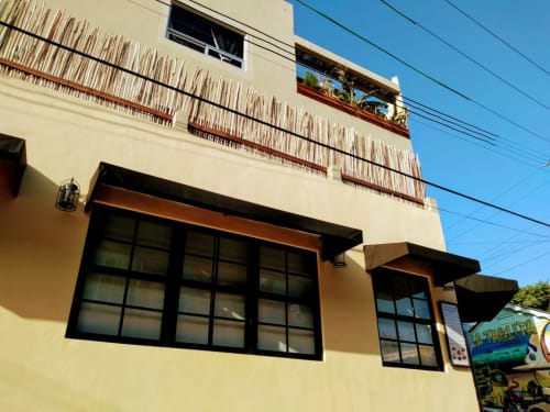 Yellow two-story villa with black-framed windows and wooden railings on terrace, Isla Mujeres