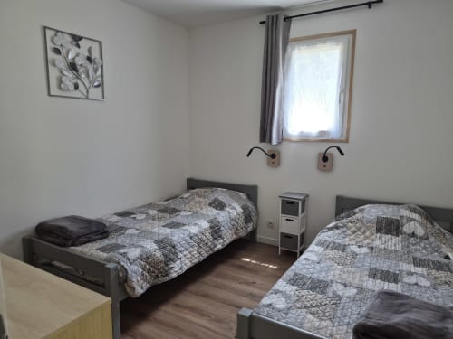 Twin beds with patterned quilts in La Boiseline cottage at Domaine en Terre Happy, Labastide-de-Virac