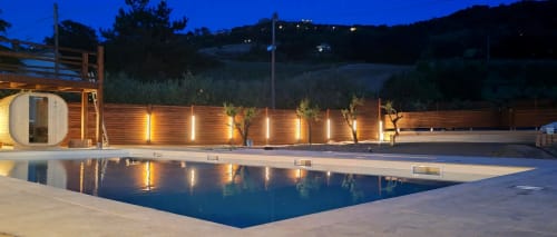 Piscina dell'hotel Queen al tramonto a Campofilone, Italia con recinzione in legno illuminata e architettura moderna