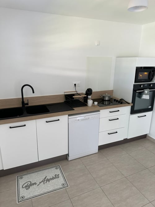Cuisine moderne du duplex Maly Blue Location au Moule avec armoires blanches et comptoirs en bois
