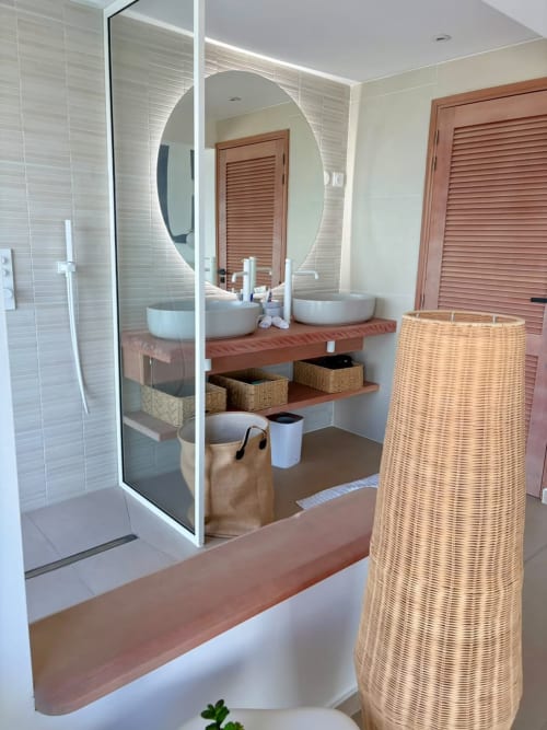 Salle de bain moderne à Maly Blue Location au Moule avec vasques doubles, miroir rond et paniers de rangement tressés