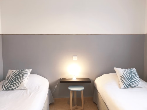 Chambre twin de la villa Residence Guddelmoni à Propriano avec oreillers rayés, lampe de chevet et tabouret en bois