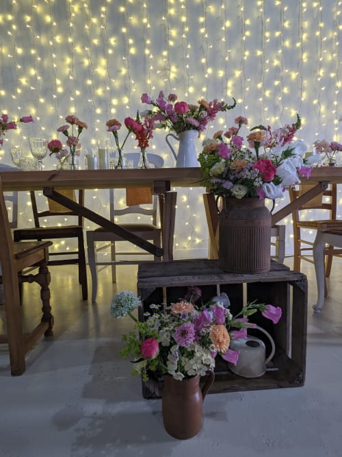 Lieu rustique élégant au Domaine De La Souche avec guirlandes lumineuses, fleurs roses et mobilier en bois créant une ambiance romantique