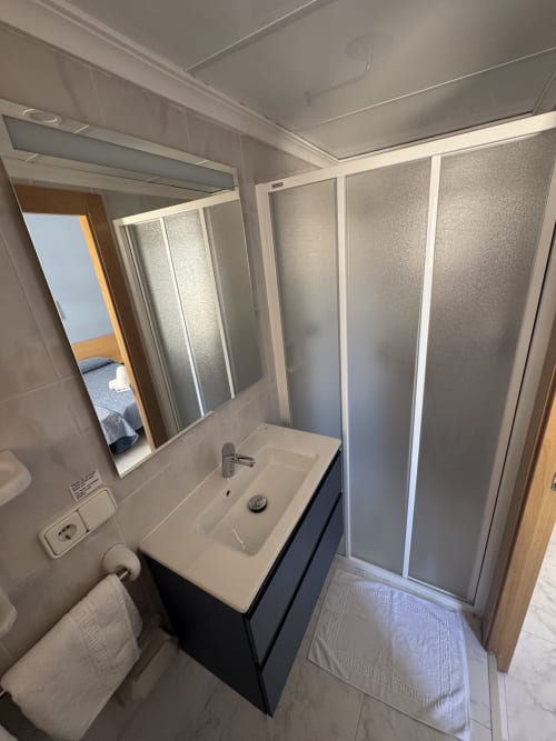 Baño moderno con lavamanos, espejo, cabina de ducha y WC en Apartamentos Playa Sol, Es Canar
