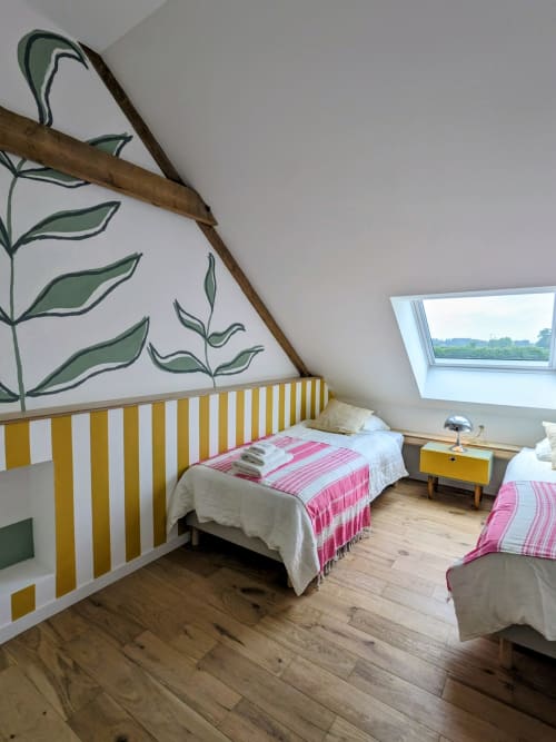 Chambre lumineuse sous les toits au Domaine De La Souche avec tête de lit rayée jaune, literie rose et art botanique mural à Rexpoëde.