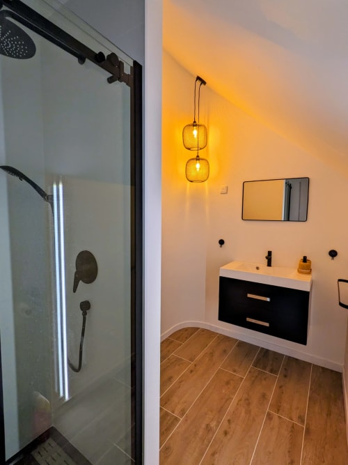 Salle de bain moderne à la Domaine De La Souche avec douche à l'italienne, vasque noire, luminaires ambrés et sol imitation bois