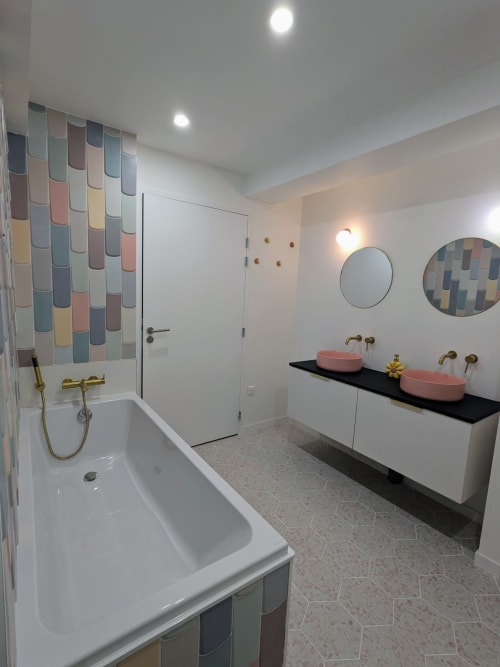 Salle de bain moderne au Domaine De La Souche avec baignoire, vasques roses doubles, carrelage coloré et accessoires dorés