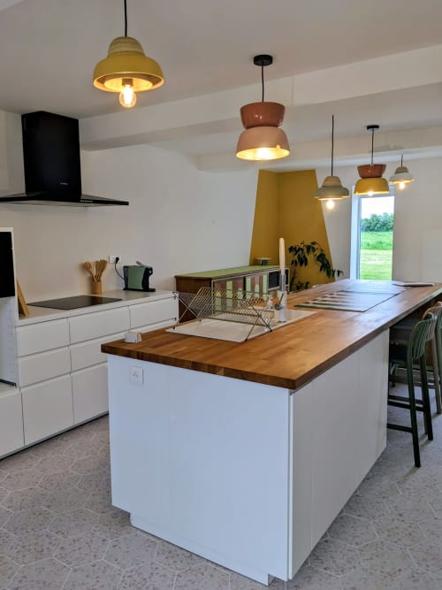 Cuisine et salle à manger modernes à la Domaine De La Souche avec îlot en bois, armoires blanches et luminaires suspension en laiton