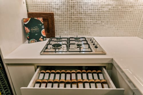 Modern kitchen with gas cooktop and open drawer displaying spice jars at Casa Rocka Boutique in Isla Mujeres