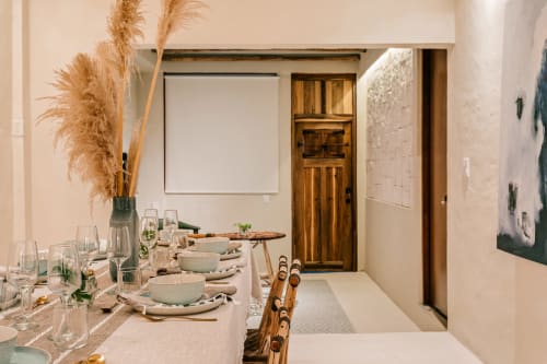 Elegant dining room at Casa Rocka Boutique in Isla Mujeres with wooden chairs, set table, pampas grass, and wooden door