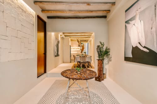 Modern entryway of Casa Rocka cottage in Isla Mujeres with white tiles, wooden beams, decorative table, and art
