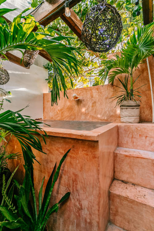 Tropical garden patio at Casa Rocka Isla Mujeres with terracotta stairs, lush palm plants, and wooden pergola overhead