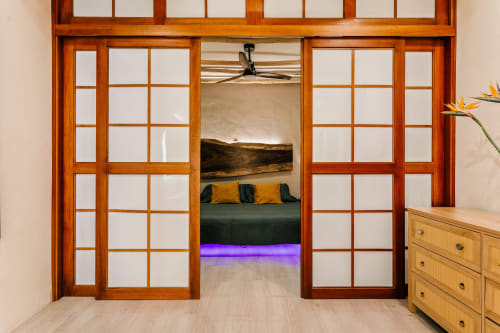 Glass sliding doors open to bedroom with green bed and yellow pillows at Casa Rocka Isla Mujeres cottage
