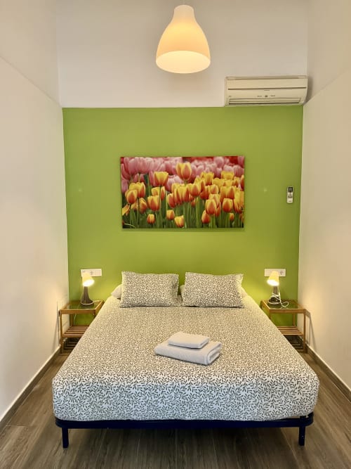 Bright bedroom with vibrant green accent wall, queen bed, tulip artwork, and modern amenities at Mira Barna apartment in