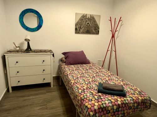Cozy bedroom in Mira Barna Barcelona apartment with colorful patterned bed, white dresser, and modern decor