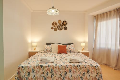 Dormitorio luminoso en el Mendez Nuñez Sunny Flat en Castelló de la Plana con ropa de cama estampada, lámparas laterales y decoración de pared
