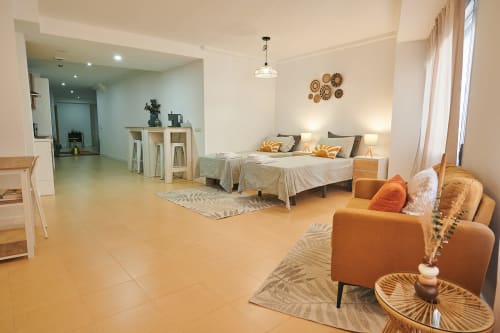 Bright studio apartment at Mediterranea Sunny Keys with bed, orange sofa, kitchenette, and city views in Castelló de la Plana